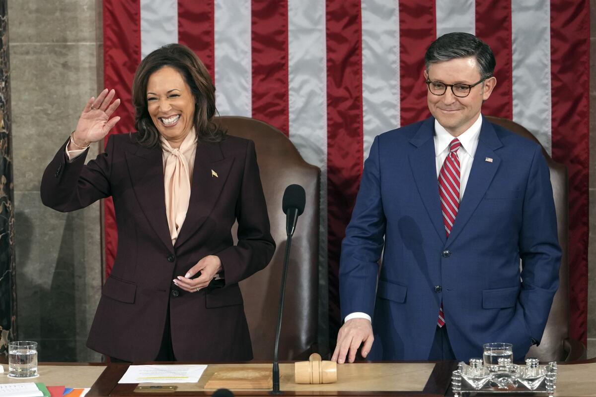 Vice President Kamala Harris smiles next to House Speaker Mike Johnson.