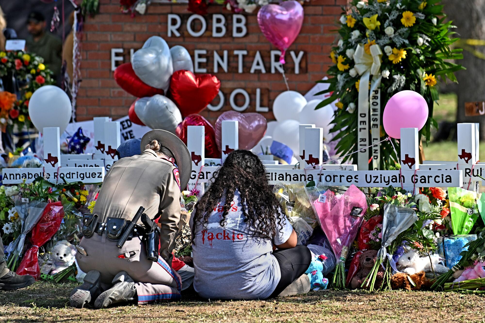 A police officer comforts family members at a memorial outside Robb Elementary School in Uvalde, Texas.